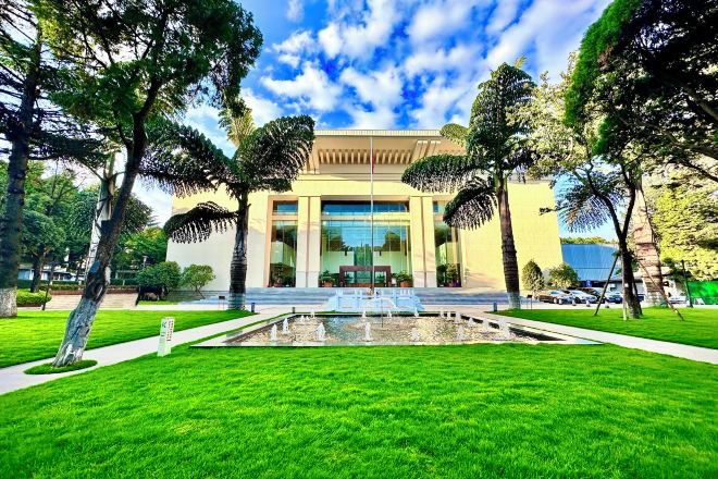 A building with a central water feature, surrounded by well-maintained grass and trees.