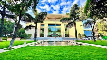 A building with a central water feature, surrounded by well-maintained grass and trees.