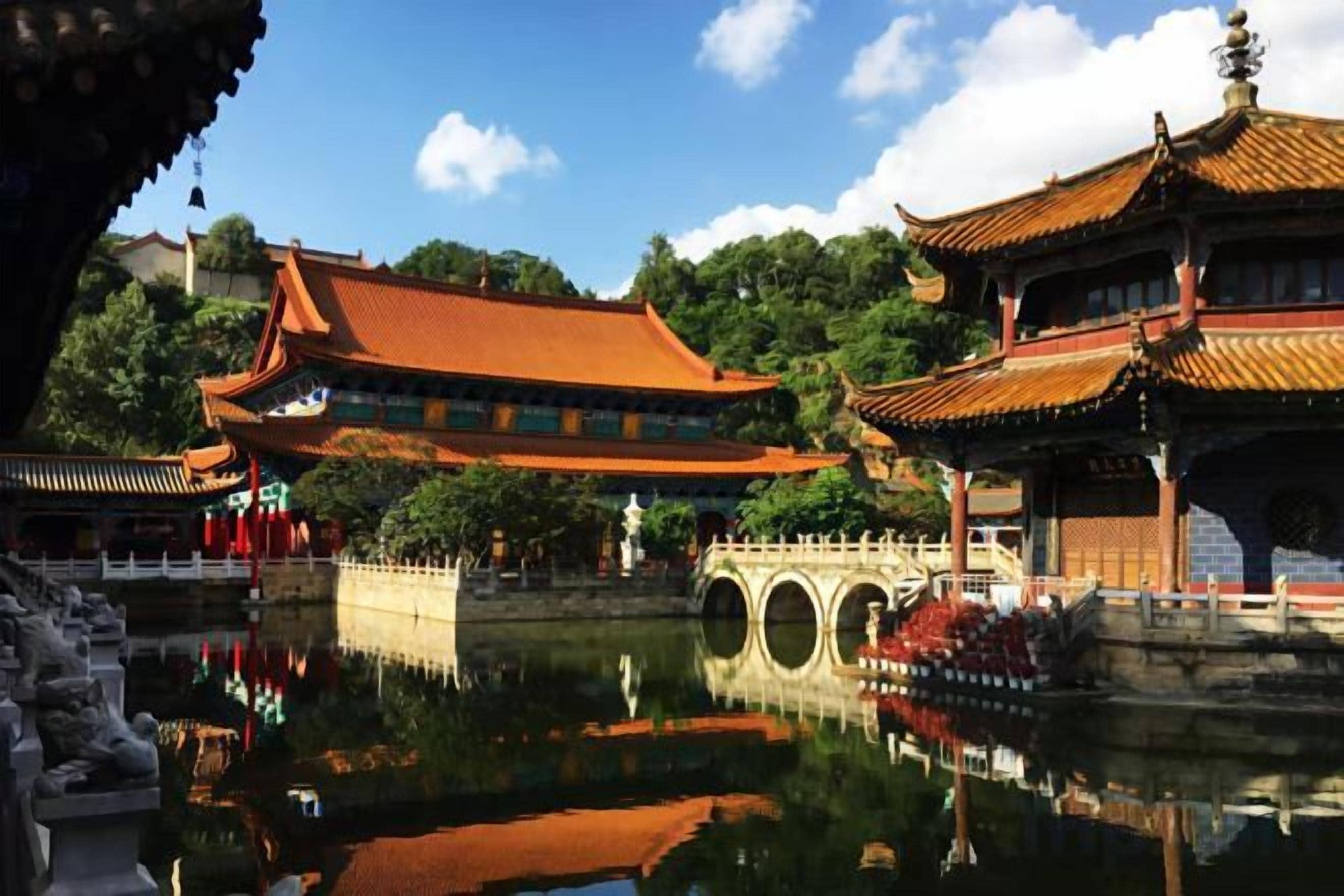 A traditional Chinese courtyard with a reflective water feature, a stone bridge, and ornate buildings.