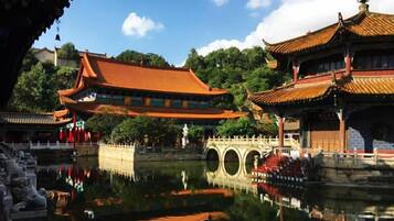 A traditional Chinese courtyard with a reflective water feature, a stone bridge, and ornate buildings.