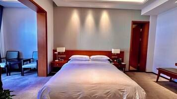 A hotel room with a large bed, bedside tables, a desk, and chairs.
