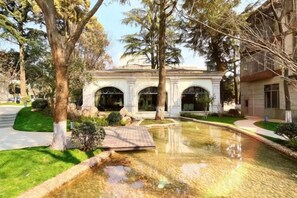 A building with three arched windows, surrounded by trees and a small water feature. - Lian Yun Hotel (Kunming)
