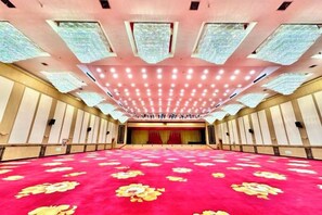 A large hall with a red carpet and a stage at the front. - Lian Yun Hotel (Kunming)