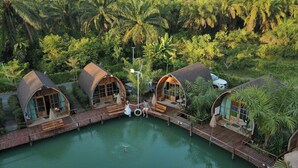 A resort with three dome-shaped cabins connected by a wooden deck over a pool, surrounded by lush greenery. - Plaiphu Pool Villas (Kapong)