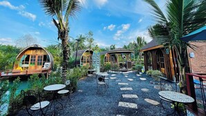 A tropical resort with wooden cabanas, outdoor seating, and a clear blue sky. - Plaiphu Pool Villas (Kapong)