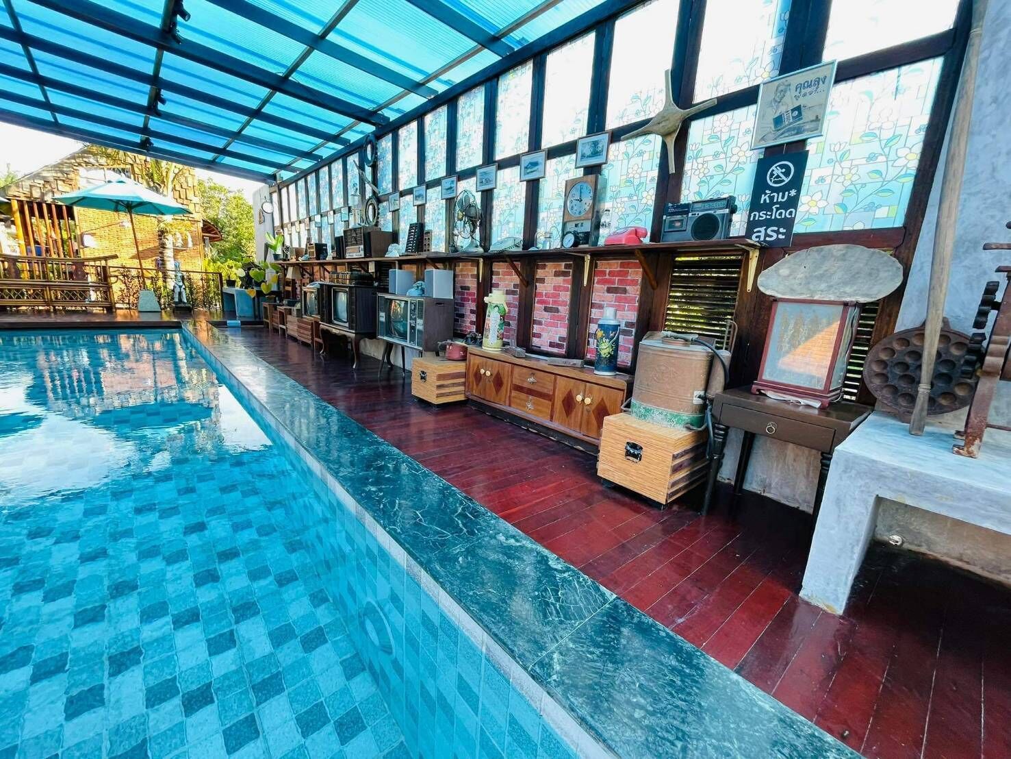 An indoor swimming pool with a glass ceiling, surrounded by vintage decor and a brick wall.