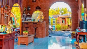 A spacious indoor area with a high ceiling, brick walls, and a central open space with a tiled floor. - Plaiphu Pool Villas (Kapong)