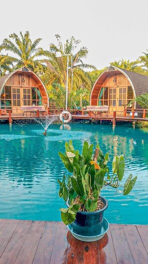 A pool area with two wooden structures, a water fountain, and a potted plant. - Plaiphu Pool Villas (Kapong)