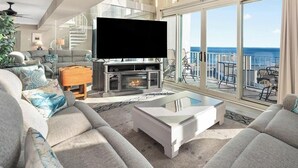 Ein geräumiges Wohnzimmer mit Kamin, bequemen Sitzgelegenheiten und einem großen Fenster mit Meerblick.