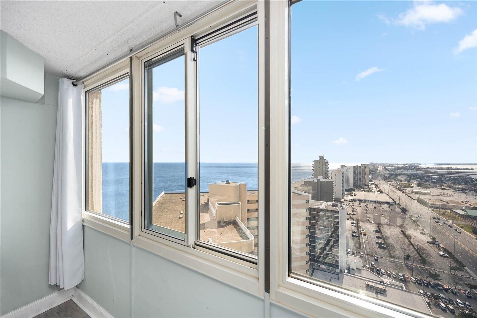Ein Zimmer mit großem Fenster und Blick auf eine Küstenstadt.