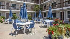 Un patio con mobiliario exterior, varios balcones y plantas en macetas.