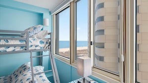 A room with a bunk bed, a desk, and a window with a view of the beach. - Quay - Direct Ocean Front 3 Bedroom Condo with Indoor & Outdoor Pools! (Ocean City)