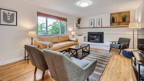 Een moderne woonkamer met een bank, fauteuils, een salontafel en een open haard.