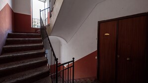 A staircase with a handrail, a wooden door, and a view of buildings outside. - Maria Theresa Rooms Garden (Naples)