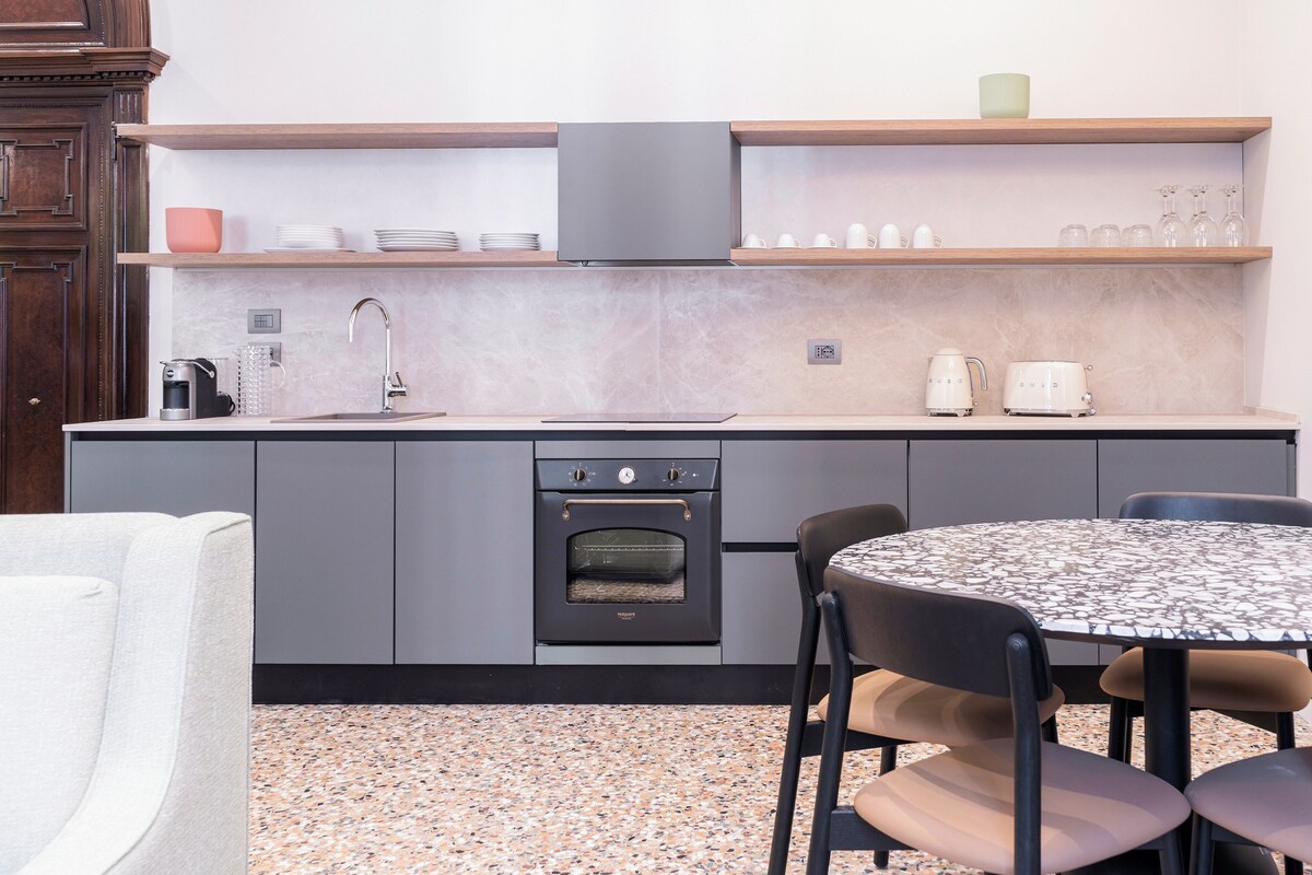 A modern kitchen with a built-in oven, a sink, and a dining table with chairs.