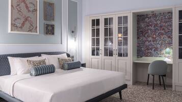 A bedroom with a bed, a desk, and a chair, a wardrobe, and artwork on the wall.