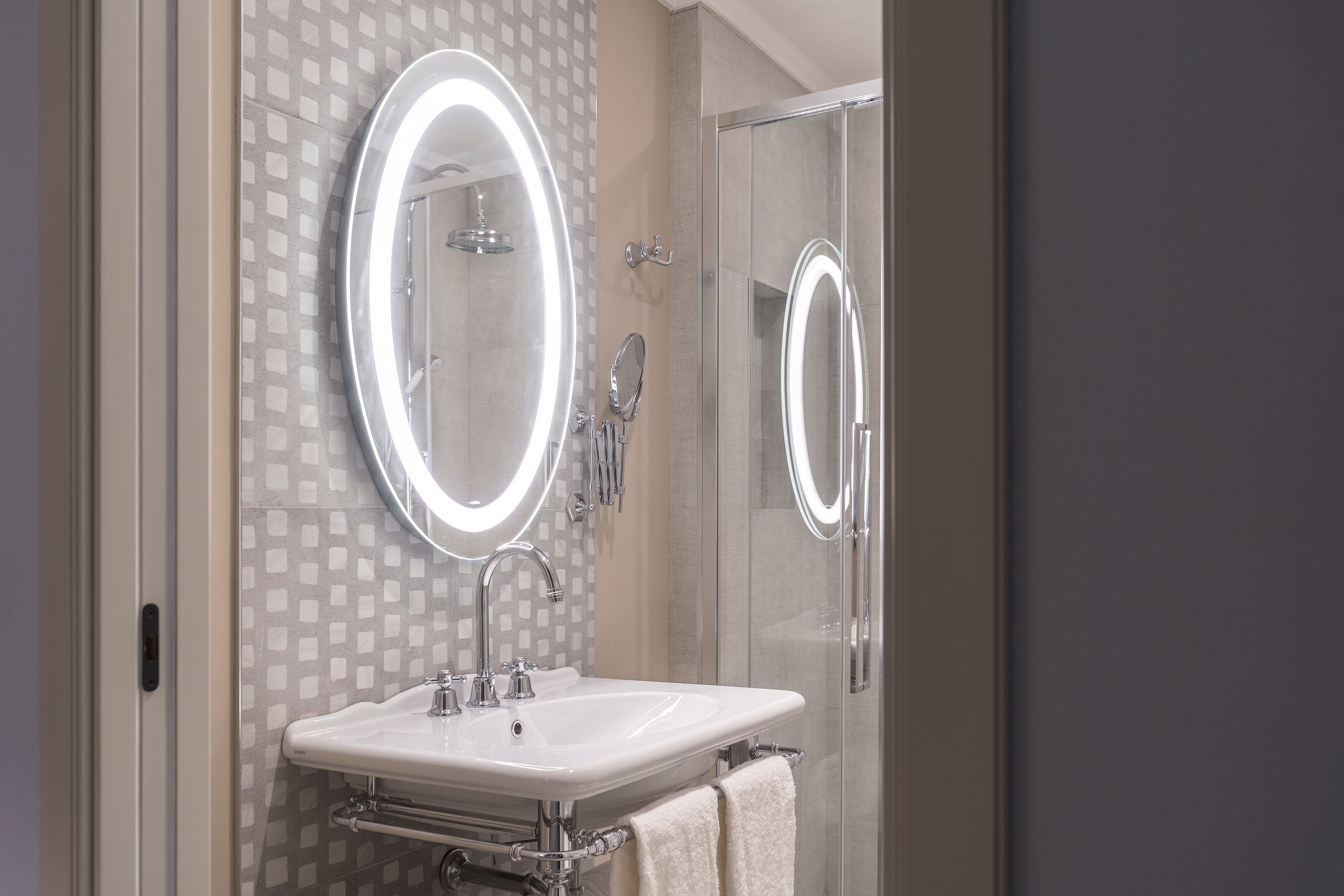 A bathroom with a glass shower enclosure, a sink with a mirror, and a towel rack.
