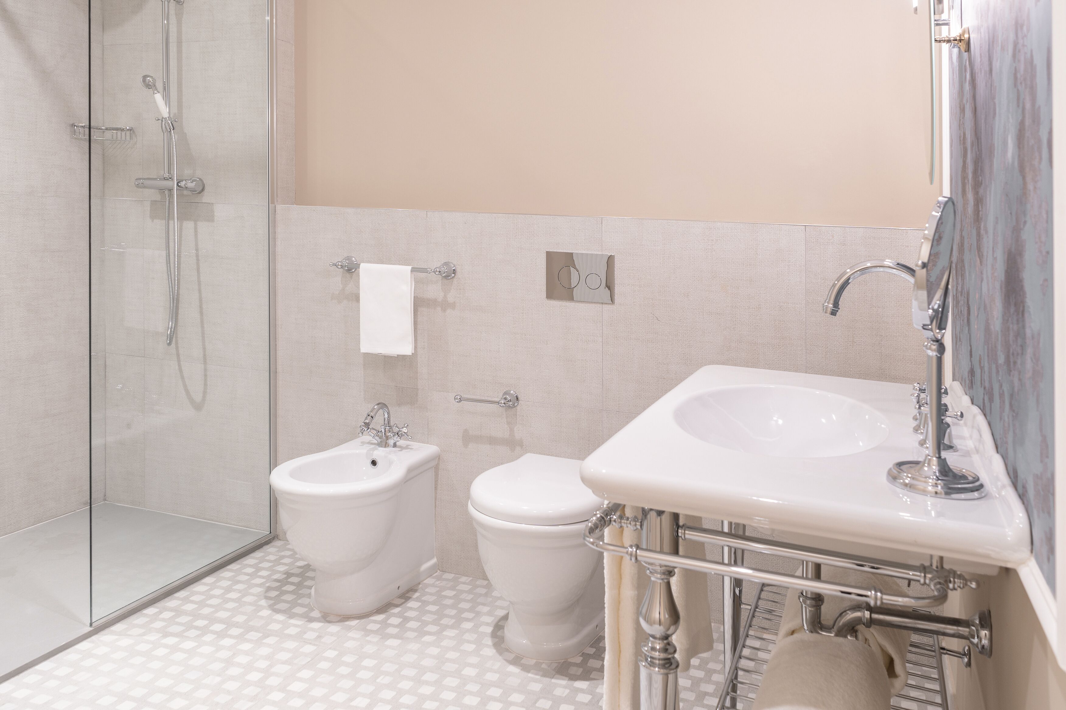 A bathroom with a glass-enclosed shower, a bidet, a toilet, and a sink with a mirror.