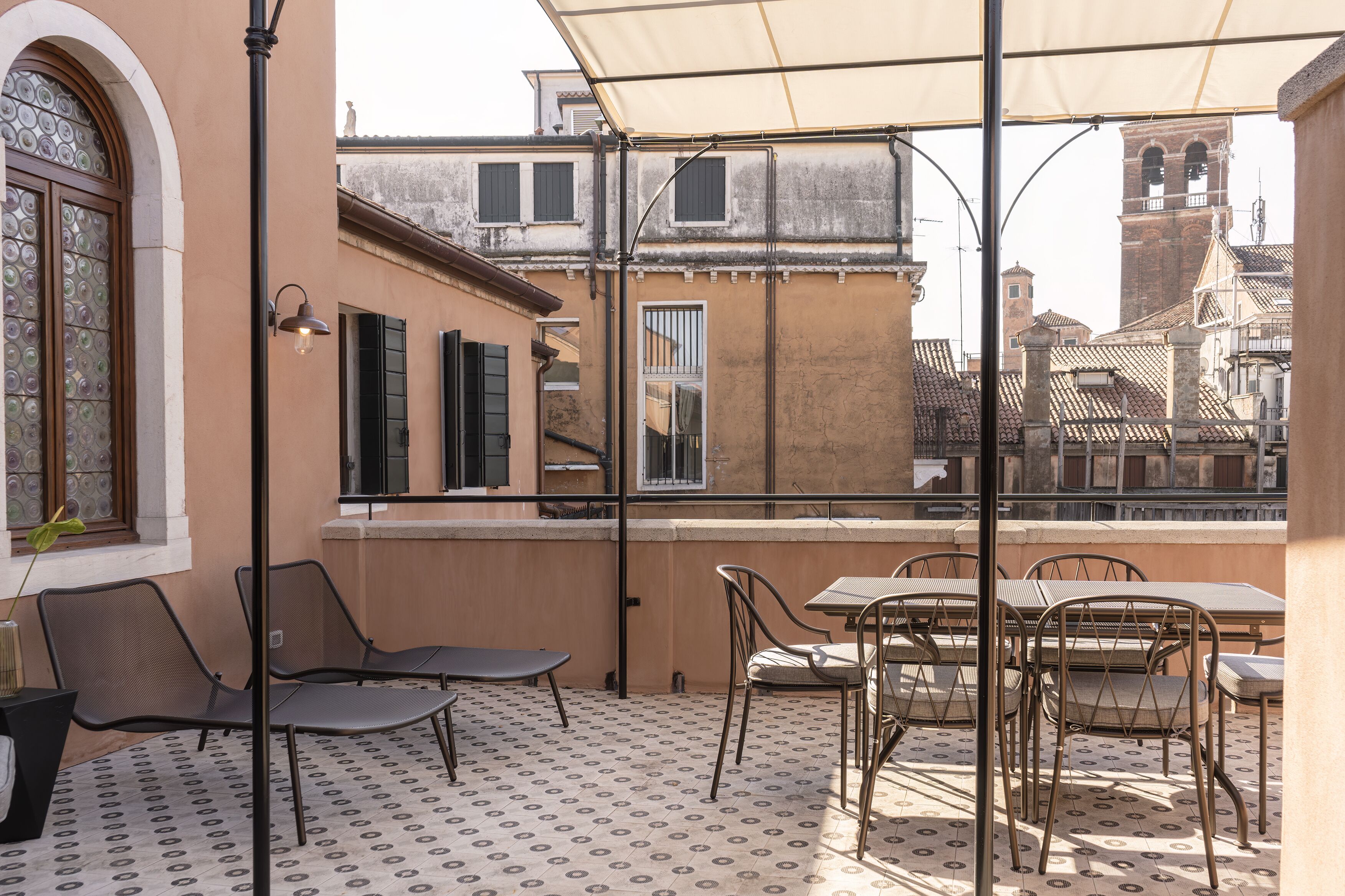 Une terrasse avec des sièges extérieurs, un sol à motifs et une vue sur des bâtiments historiques.