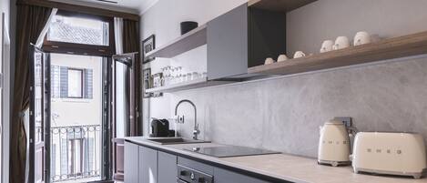 Una cocina moderna con horno empotrado, un lavabo y una cafetera.