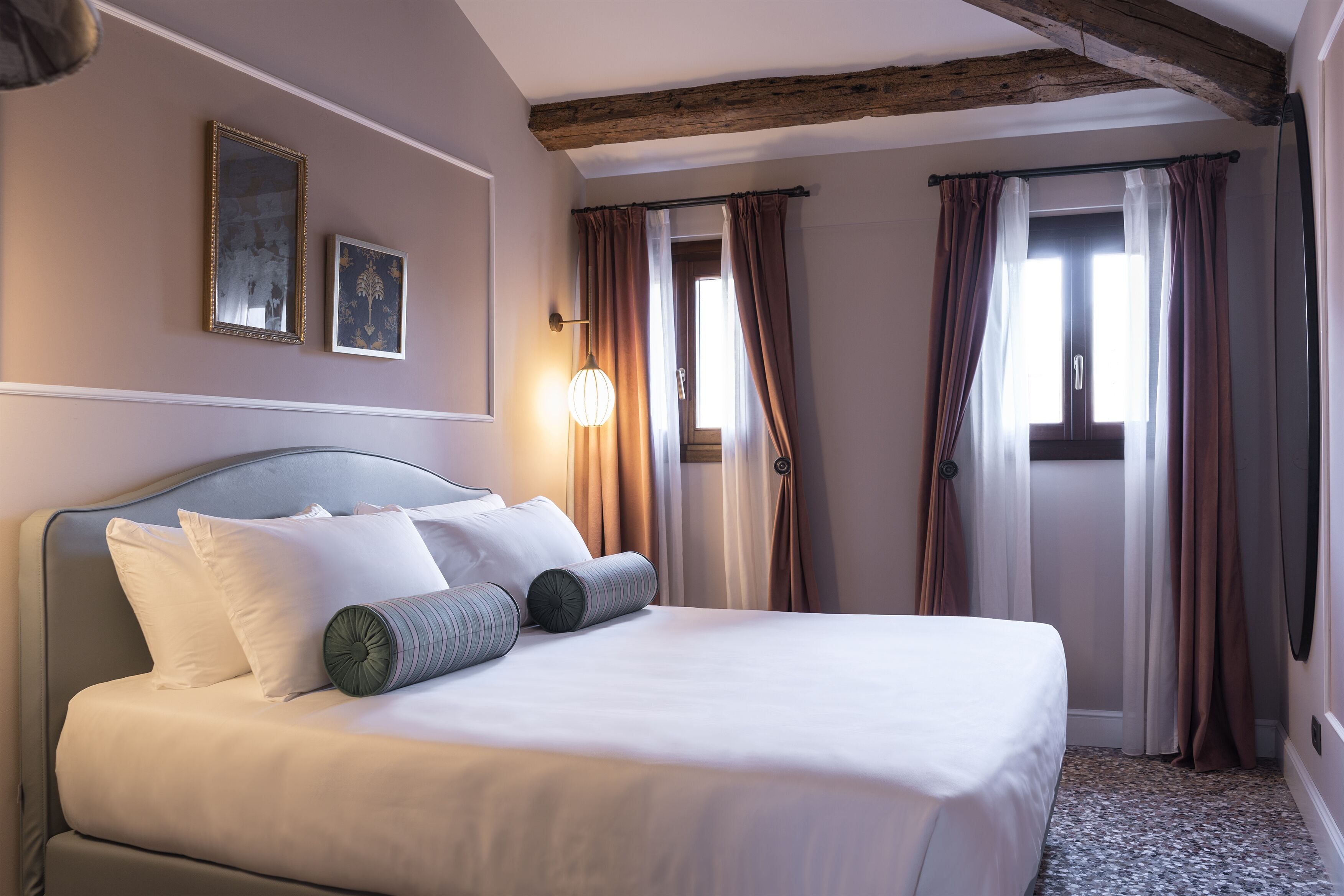 Un lit bien fait, avec des oreillers, une tête de lit et une lampe fixée au mur.