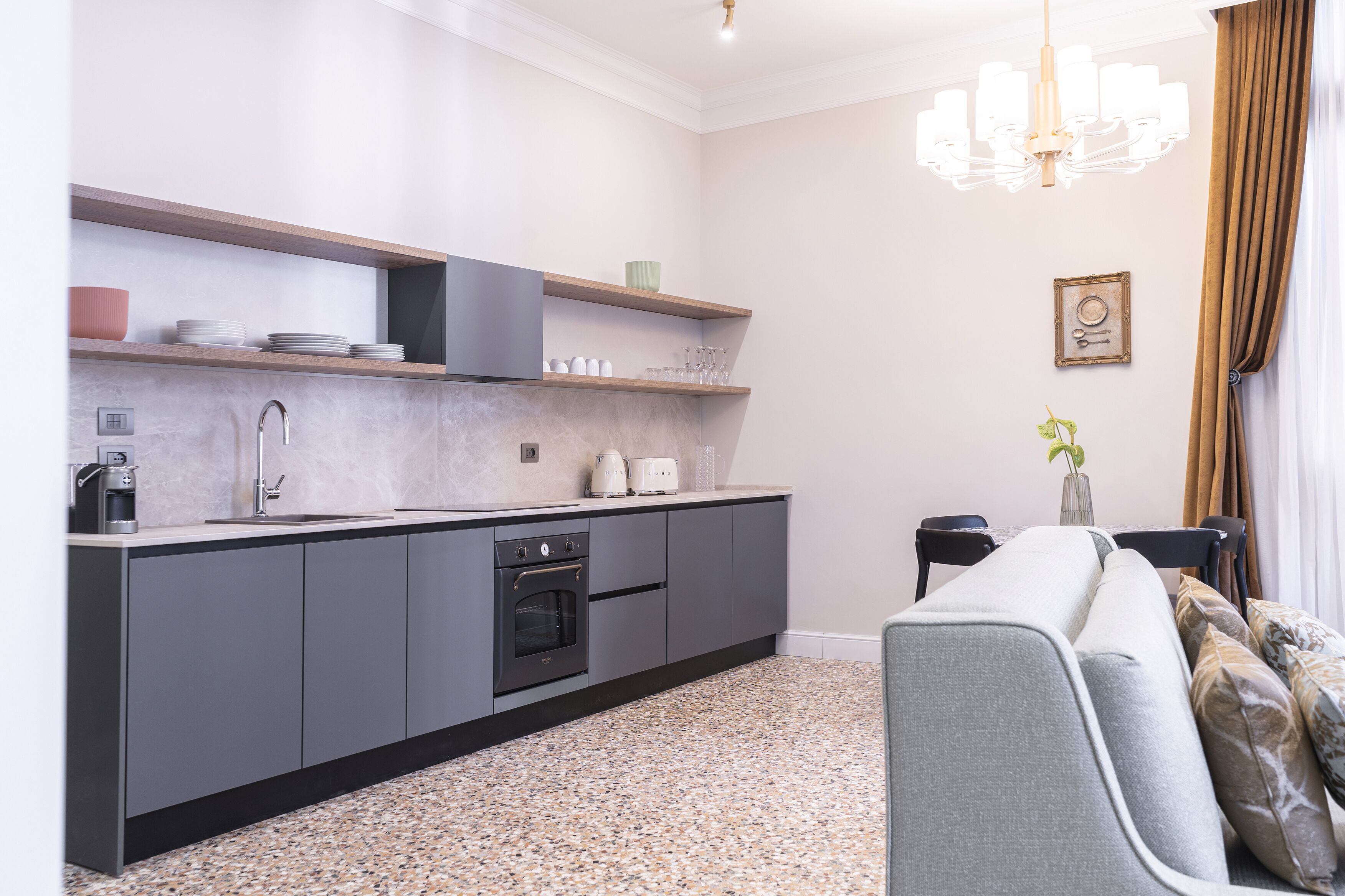 Eine moderne Küche mit grauen Schränken, einem eingebauten Backofen und einer Arbeitsplatte mit Kaffeemaschine.