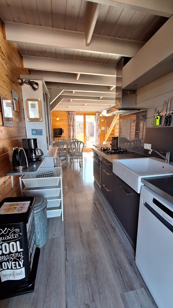 A modern kitchen with wooden accents, a dining area, and a view into the living space.