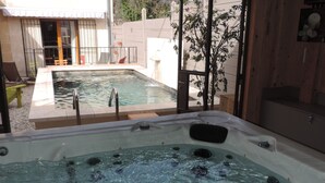 Ein Whirlpool mit Blick auf einen Pool und eine Holzterrasse.