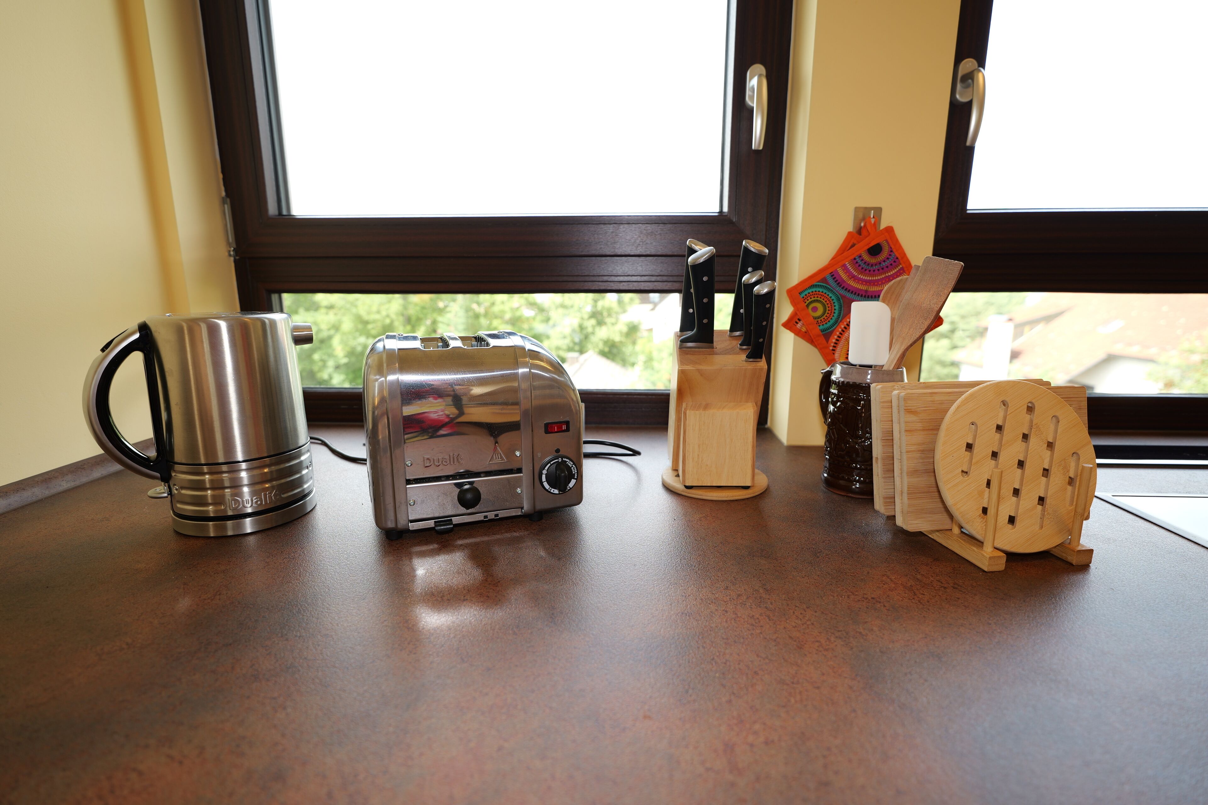 A kitchen counter with a toaster, a kettle, and a knife block.