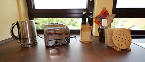 A kitchen counter with a toaster, a kettle, and a knife block.