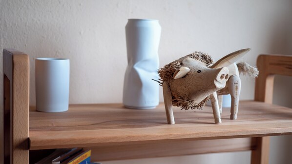 A wooden shelf with a decorative animal figure, a white vase, and a cylindrical container.