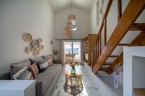 A spacious living area with a sofa, decorative pillows, a round coffee table, and a staircase leading to an upper floor. - Grand Bleu Anastazia (Ermionida)