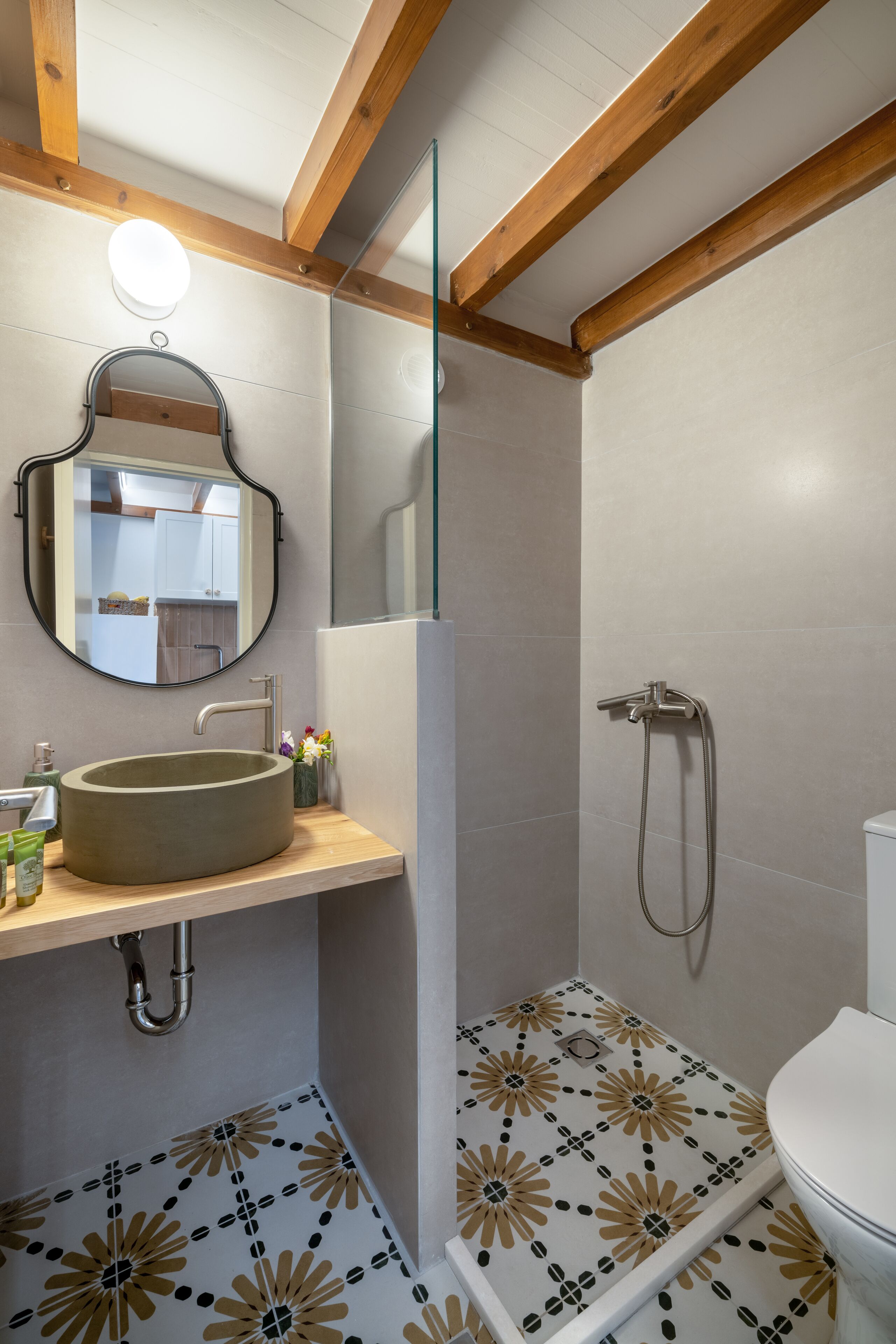 A bathroom with a round sink, a mirror, a shower, and a toilet.