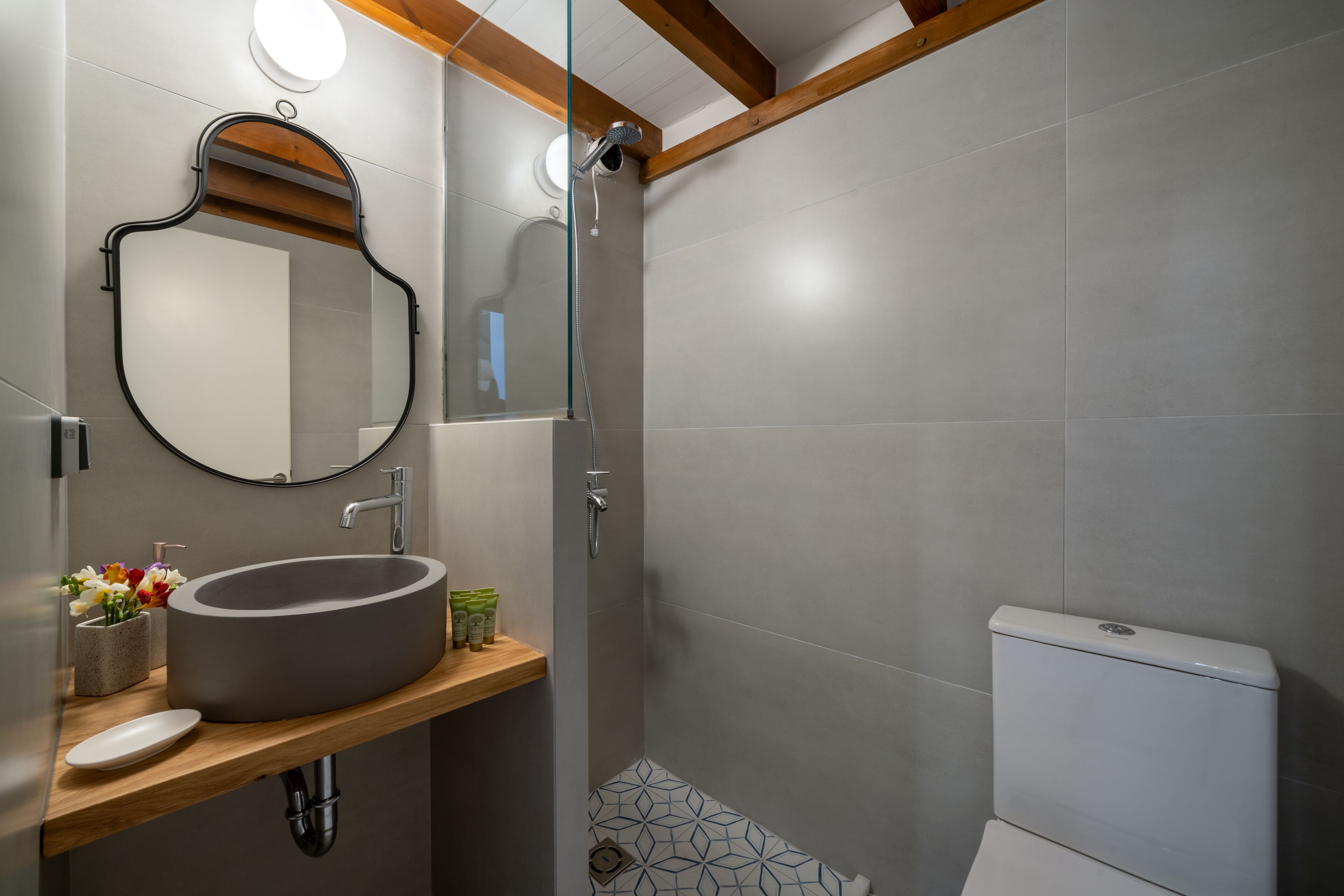 A modern bathroom with a large oval sink, a round mirror, a toilet, and a shower area.