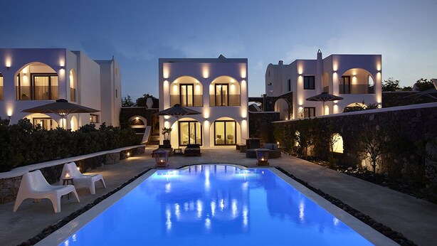 Una villa moderna con piscina, mobiliario exterior y arquitectura bien iluminada.
