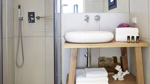 Un baño moderno con cabina de ducha de vidrio, tocador de madera y un espejo grande.