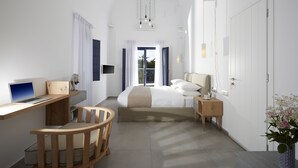 Un dormitorio moderno con cama, escritorio, silla, mesita de noche y un jarrón de flores.