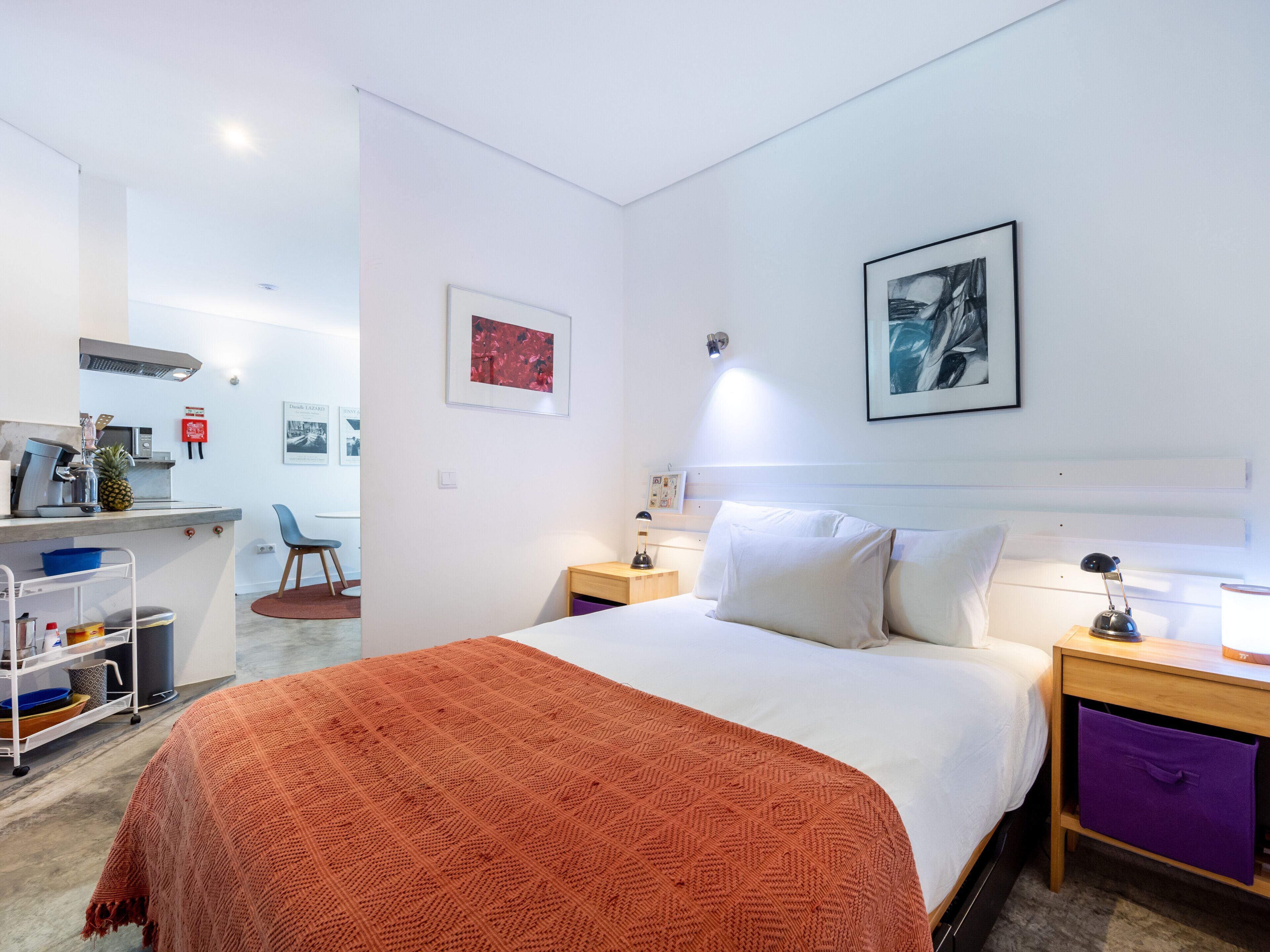 Et hotelværelse med seng, skrivebord, stol og tekøkken.