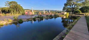 A serene outdoor pool area with lounge chairs and a wooden deck. - Nature gite, natural swimming pool, sauna, Nordic bath, farmhouse (Augerolles)
