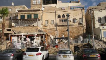 A street view with parked cars, a building with a sign for a roofing service, and a staircase leading to an upper level.