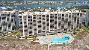 A high-rise apartment building with multiple balconies, a swimming pool, and a view of a marina.