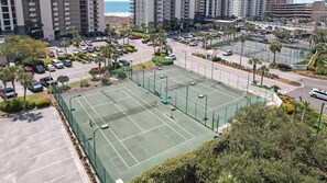 A multi-level parking structure with a tennis court in the foreground.
