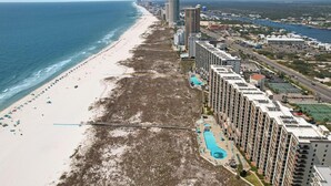 Un hôtel situé sur la côte, avec vue sur la plage, plusieurs piscines et un parking.