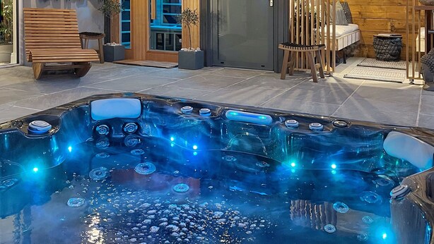 Area spa esterna moderna con vasca idromassaggio, terrazza in legno e schermo televisivo a parete.