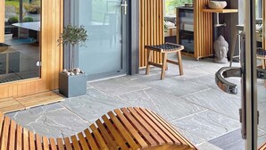 Un interno moderno con una panca in legno, una porta vetrata e vista sull'esterno.