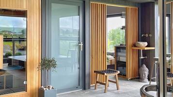 A modern interior with a wooden bench, a glass door, and a view of the outdoors.