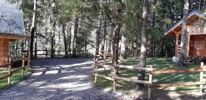 A wooden cabin surrounded by a gravel path and a wooden fence, set in a forested area with tall trees. - CHALET L'UBAC, a little corner of paradise between Lake Annecy and its mountains (Bluffy)