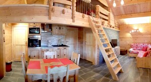 A wooden cabin interior with a kitchen, dining area, and a loft bedroom. - CHALET L'UBAC, a little corner of paradise between Lake Annecy and its mountains (Bluffy)