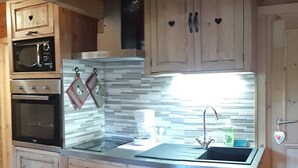 A kitchen with wooden cabinets, a stainless steel sink, and a microwave. - CHALET L'UBAC, a little corner of paradise between Lake Annecy and its mountains (Bluffy)