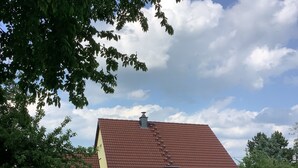 Keltainen talo, jossa on punainen katto, suuret ikkunat ja nurmikkoinen piha.